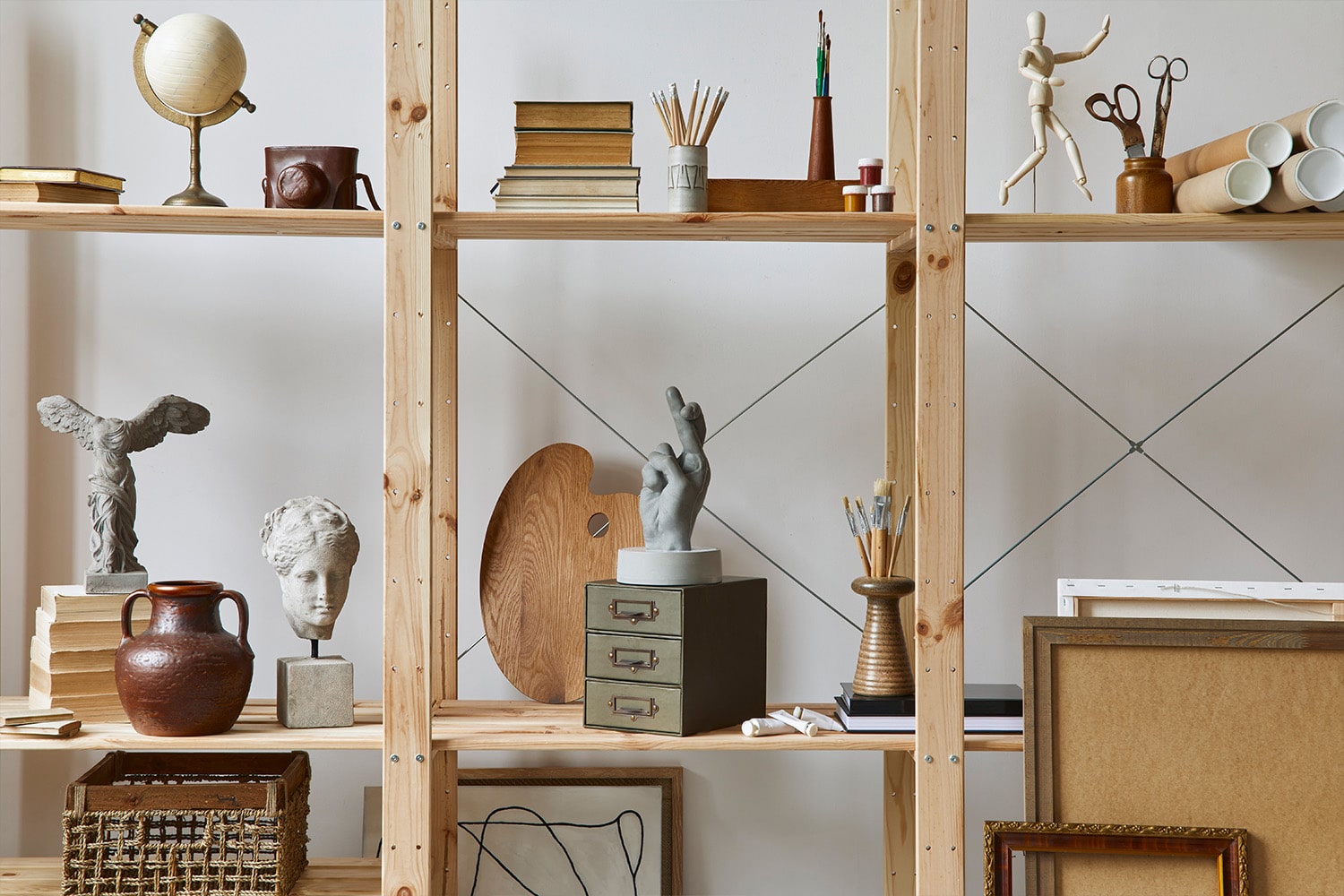 Wooden shelves with art books, busts, and creative decor in a stylish modern living space.