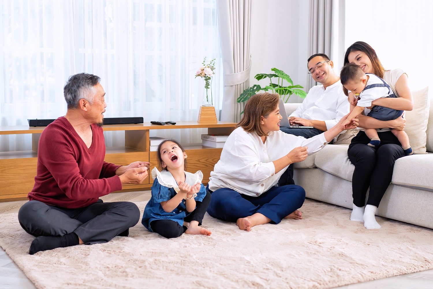 Three generations of a happy family enjoying time together in a bright condo living room.